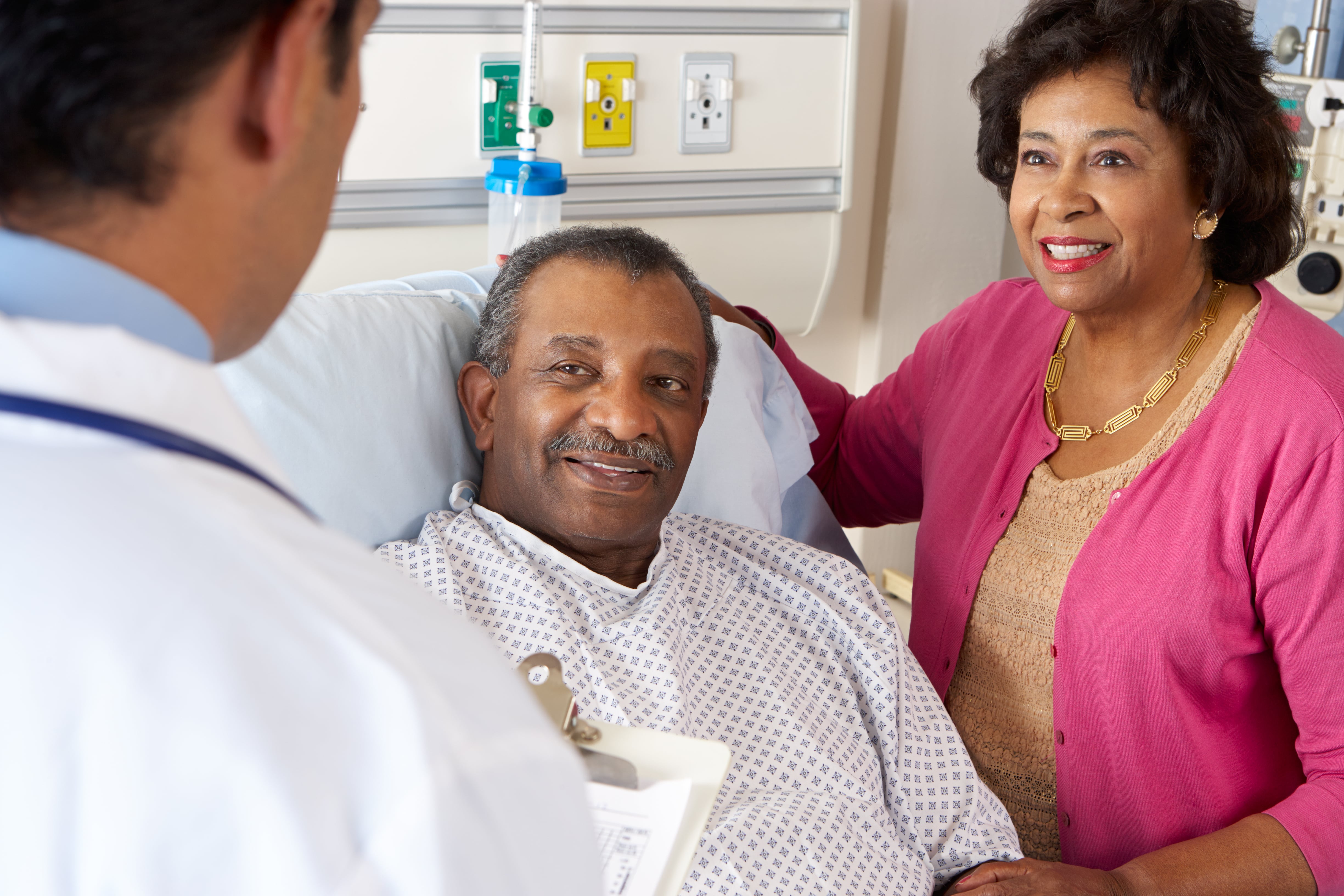 An hospitalized older adult and his caregiver listening to the doctor