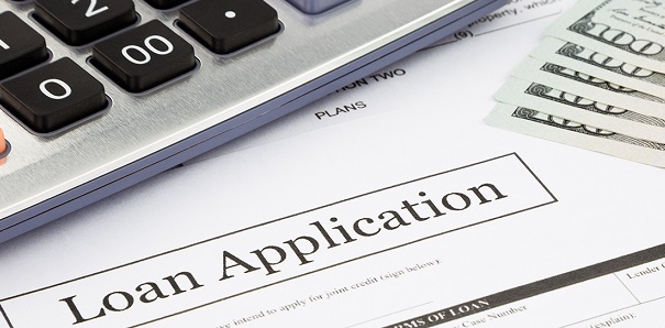 A loan application, calculator, and five hundred dollar bills