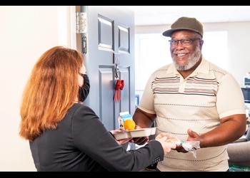 An older adult receiving a meal delivery from a volunteer