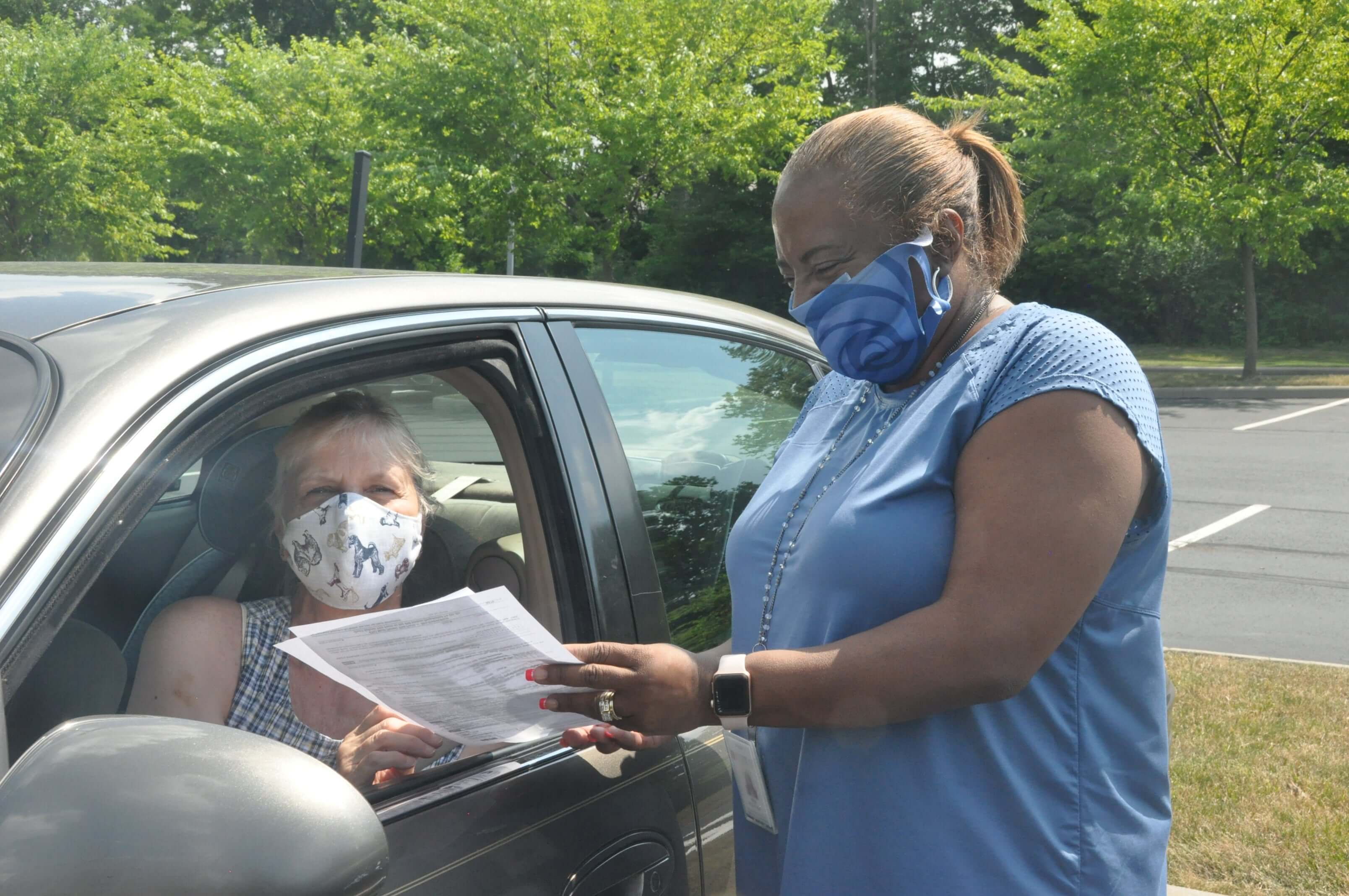 A Benjamin Rose employee passing documents to a woman in a car