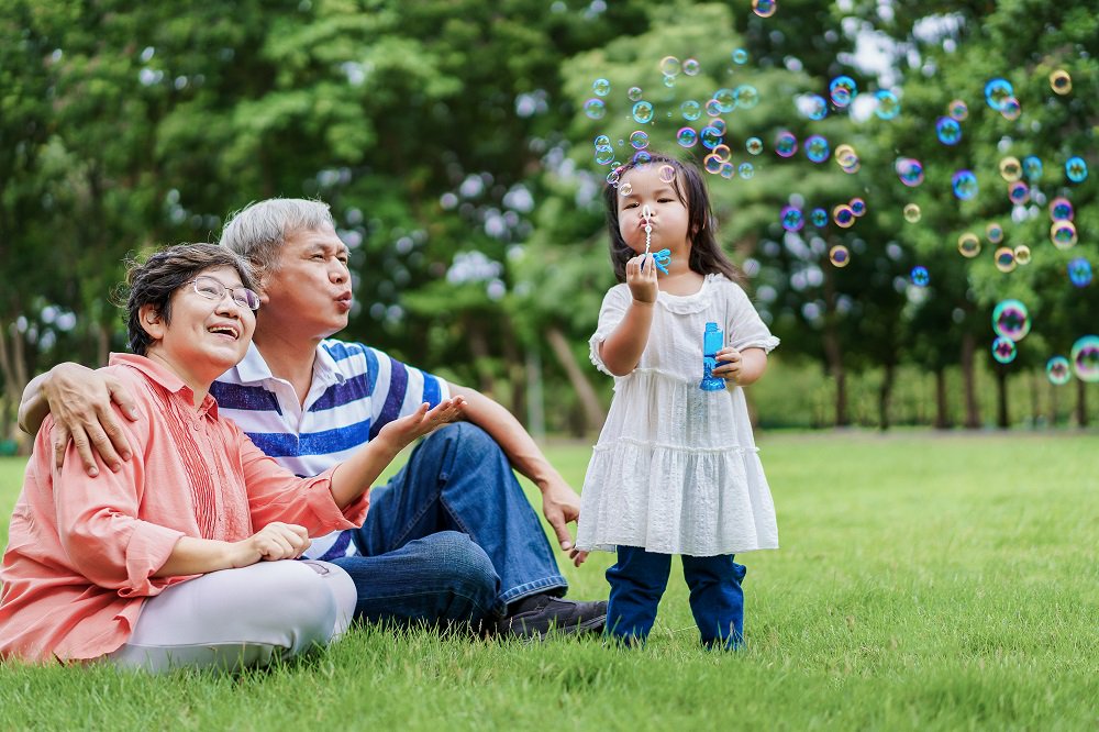Grandparents watching their granddaughter blow bubbles