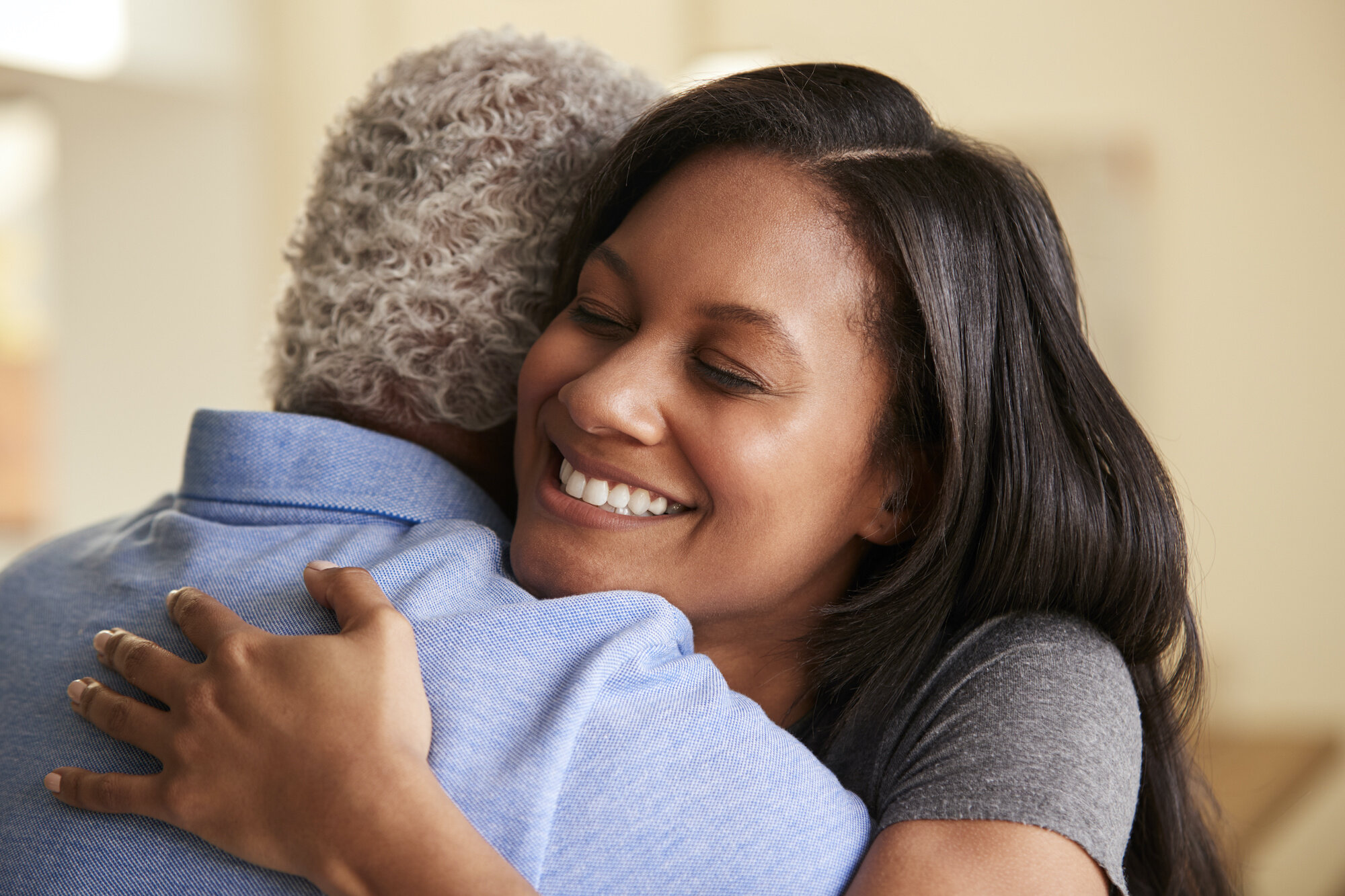 A caregiver joyfully embracing her older loved one