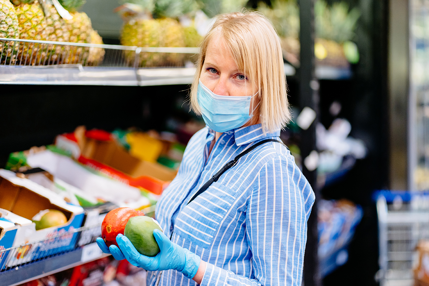 A woman shopping for groceries with a protective mask and gloves